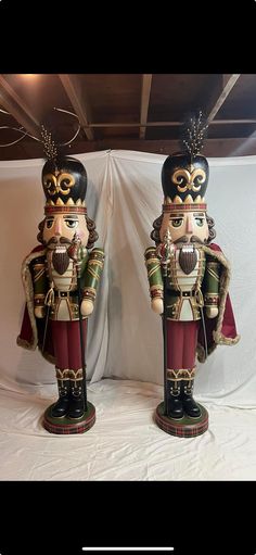 two wooden nutcrackers standing next to each other in front of a white backdrop