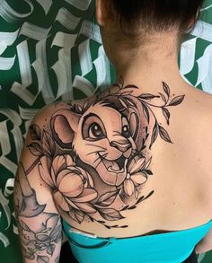 the back of a woman's shoulder with an elephant and flowers tattoo on it