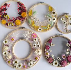 four embroidery hoops with flowers in them on a white surface, each decorated with an individual's own design