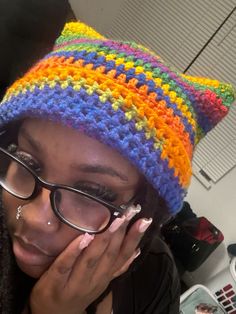 a woman wearing glasses and a multicolored crocheted hat covering her face