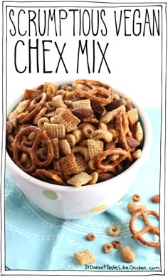 a white bowl filled with chex mix on top of a blue cloth next to pretzels