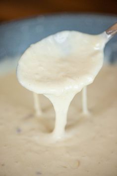 a spoon full of cream is being held over the top of a saucepan filled with liquid