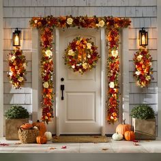 a front door decorated for fall with pumpkins and wreaths on the side wall