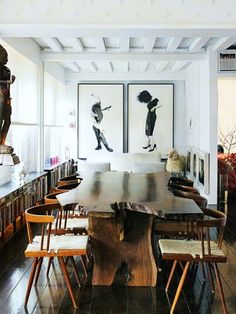 a large wooden table surrounded by chairs in a room with bookshelves and pictures on the wall