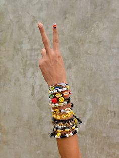 a woman's hand with bracelets and rings on it making the peace sign