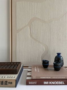 two vases sitting on top of books next to each other in front of a wall