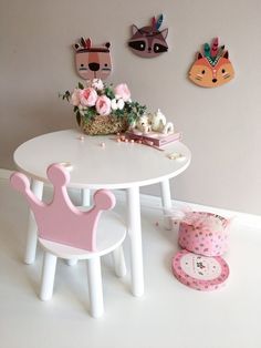 a white table topped with a pink princess crown next to a wall mounted animal head