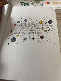 an open notebook with writing on it and space related items around the page in front