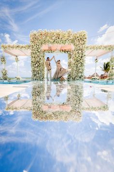 two people are standing in front of a wedding arch