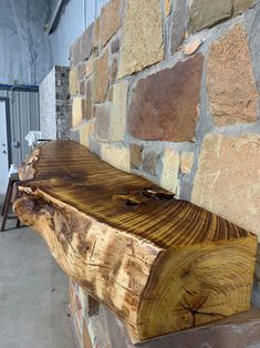 a wooden bench sitting next to a brick wall in a room with stone walls and flooring