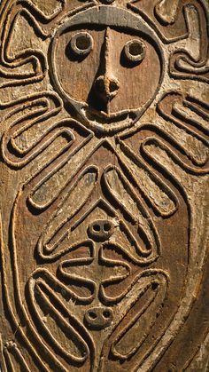 an intricate carving on the side of a wooden structure with faces and words written in cursive writing