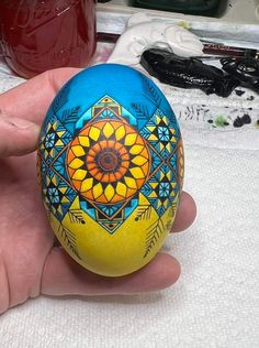 a hand holding an egg painted with colorful designs