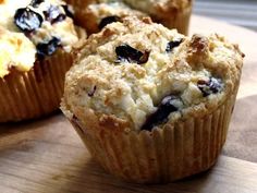 three blueberry muffins sitting on top of a wooden table