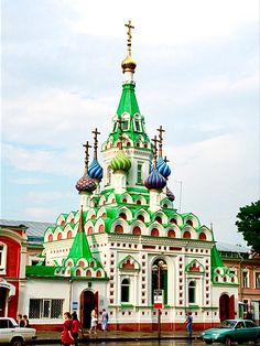 a large white and green building with lots of domes on it's sides in the middle of a street