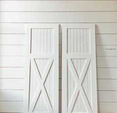 two white wooden doors on the side of a wall