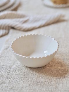 a white bowl sitting on top of a table next to other plates and napkins