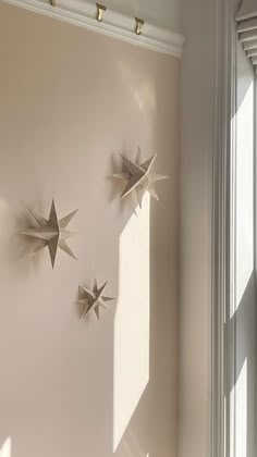 three metal stars hanging from the side of a wall next to a window in a room