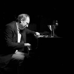 a man sitting at a piano in the dark