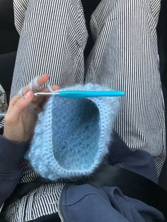 a person holding a toothbrush in their left hand and a crocheted cup holder