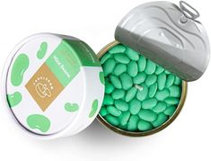 a tin filled with green and white candies next to a container of mints