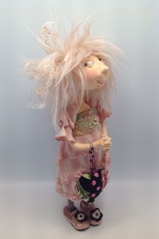 the doll is dressed in pink and has feathers on her head