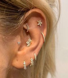 a close up of a person wearing ear piercings with flowers on the outside of their ears