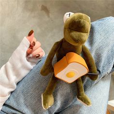 a stuffed animal sitting on top of a person's lap next to an egg frying pan