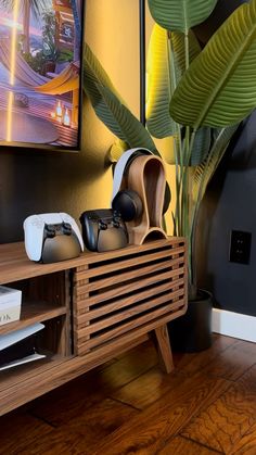 a wooden shelf with video game controllers on it in front of a painting and palm tree