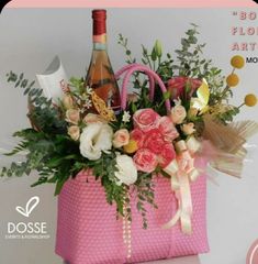 a pink bag with flowers and wine in it sitting on top of a white table