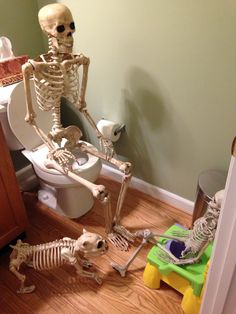 a skeleton sitting on top of a toilet next to a child's play set