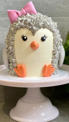 a cake decorated like a penguin with a pink bow on it's head and eyes