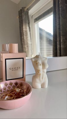 a pink bowl sitting on top of a counter next to a bottle of gucci bloom