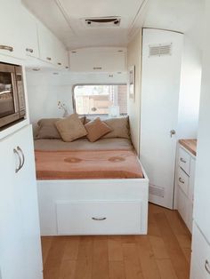 a kitchen area with a bed, microwave and cupboards in an rv or camper