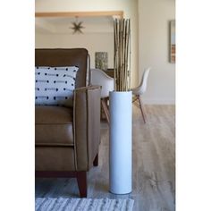 a white vase sitting on top of a wooden floor next to a chair and table