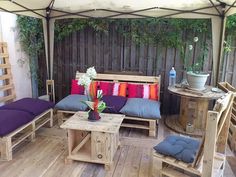 a patio with wooden furniture and purple cushions