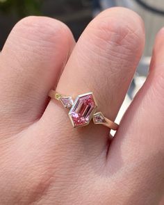 a woman's hand with a pink diamond ring on it