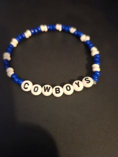 a beaded bracelet with the word cowboys written in white and blue beads on it