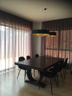 a dining room table with black chairs and curtains