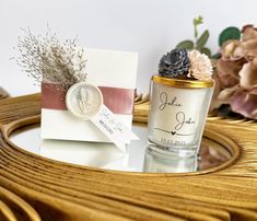 a vase with flowers and a card on a table next to some other items that are sitting on a wicker basket