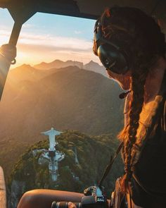 a woman sitting in the cockpit of an airplane looking out over a valley and mountain