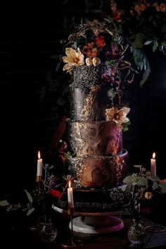 a three tiered cake sitting on top of a table next to two lit candles