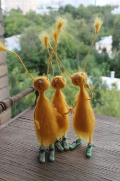 three little yellow birds are hanging from a wooden pole with their legs in the air