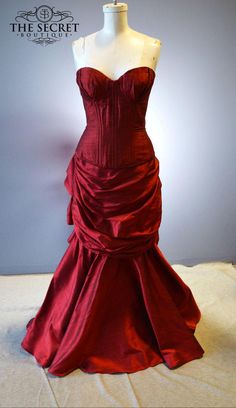 a red dress is on display in front of a gray wall with the words, the secret