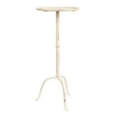 a white table with an iron stand on it's legs and a round top