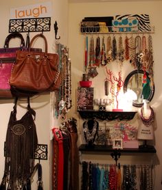 there are many purses and jewelry on the shelves in this room, all hanging up