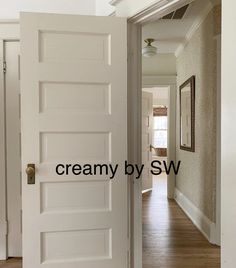 an open door leading to a hallway with hardwood floors and white paint on the walls