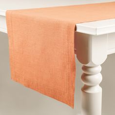 an orange linen table runner on top of a white table