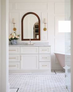 a bathroom with white cabinets and marble counter tops is seen through an open doorway that leads to the bathtub