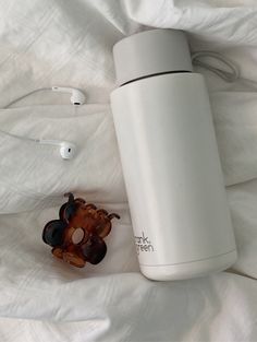 thermos and earbuds are laying next to each other on a bed