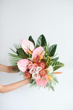 a woman holding a bouquet of flowers in her hands on a white background with greenery